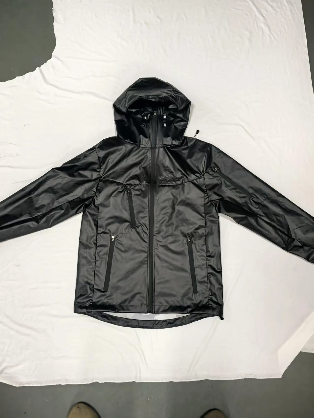Black windbreaker laid flat on white fabric