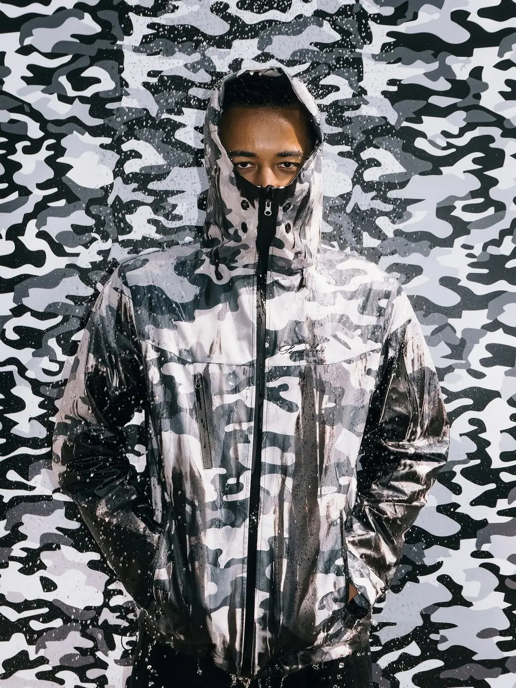 Model in the snow camo windbreaker with water beading on the surface
