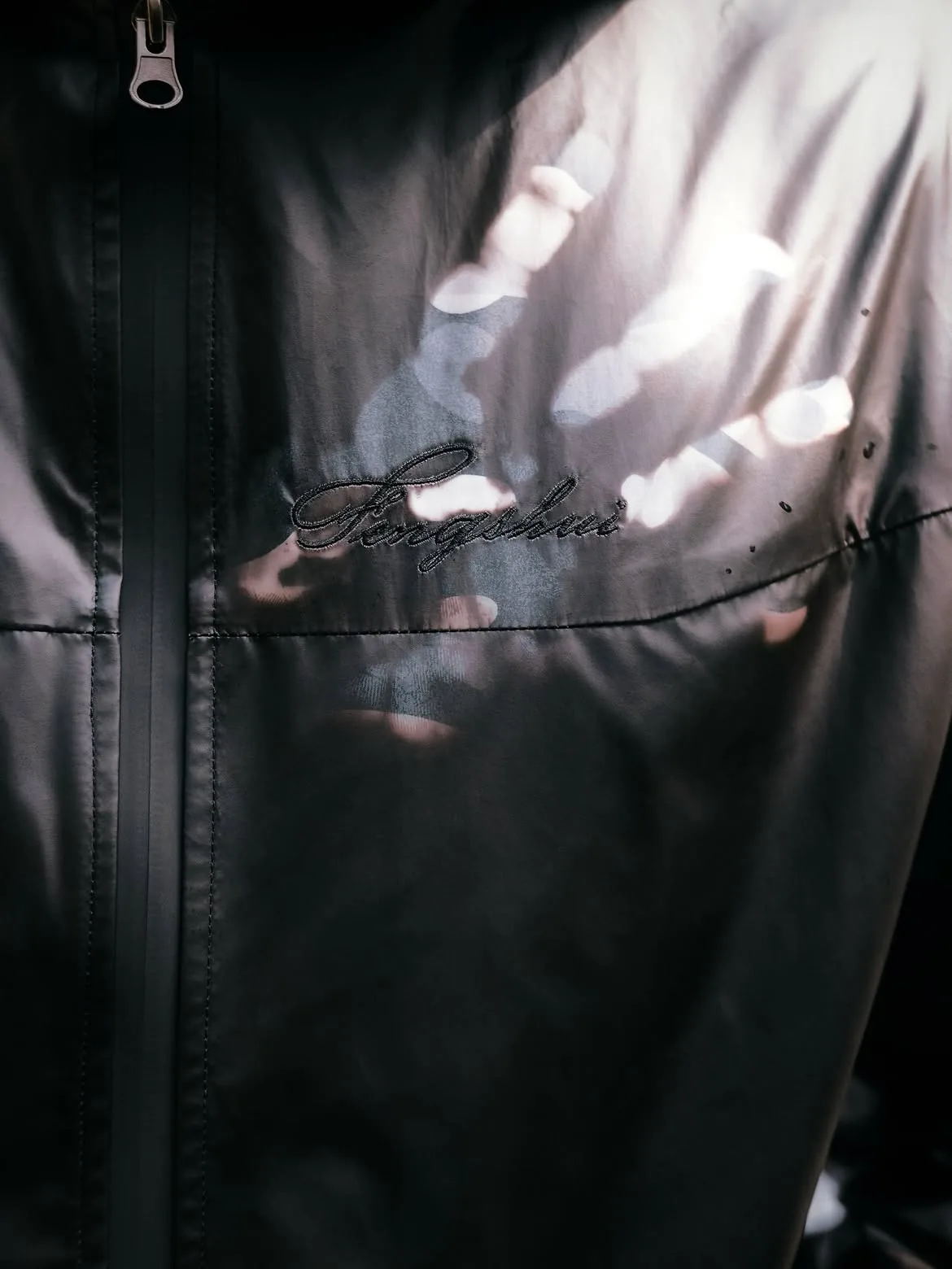 Close-up of the chest script logo and zipper on the windbreaker