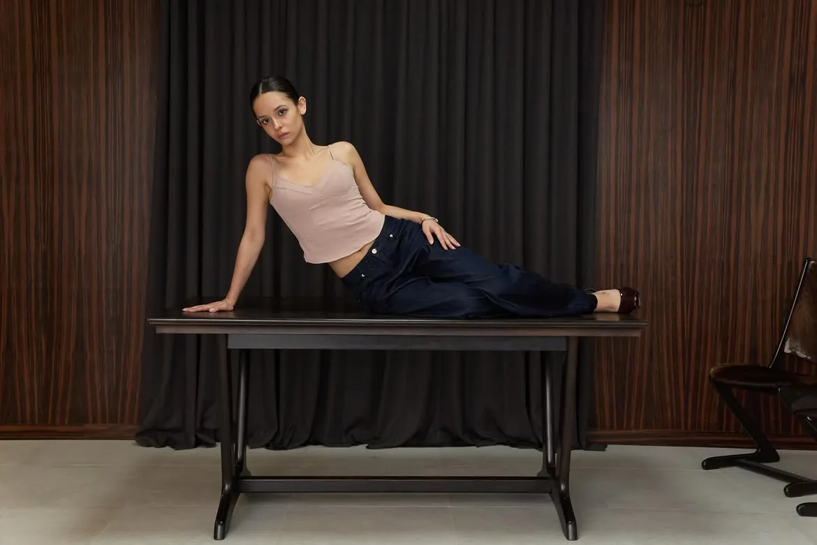 Model sitting at an angle on a table wearing the cami top